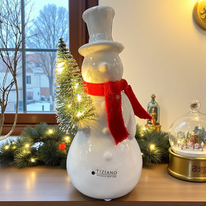 Ein creme-weißer Keramik Schneemann mit rotem Schal und beleuchtetem Tannenbaum, Serie Sören von Tiziano im Ambiente