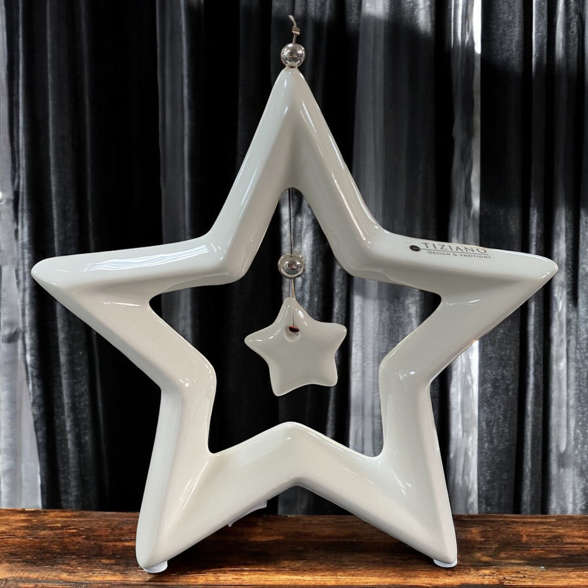 Ein creme-weißer Keramik Stern Saphira mit kleinem hängenden Stern in der Mitte im Ambiente