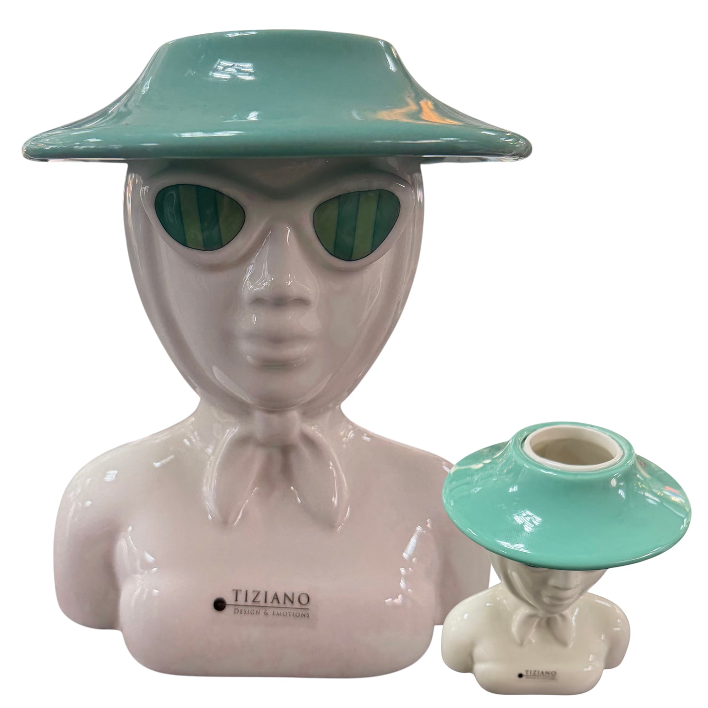 Eine weiße Keramik-Büste mit grüner Sonnenbrille und türkisfarbenem Hut steht vor weißem Hintergrund, daneben liegt der abnehmbare obere Teil der Vase.