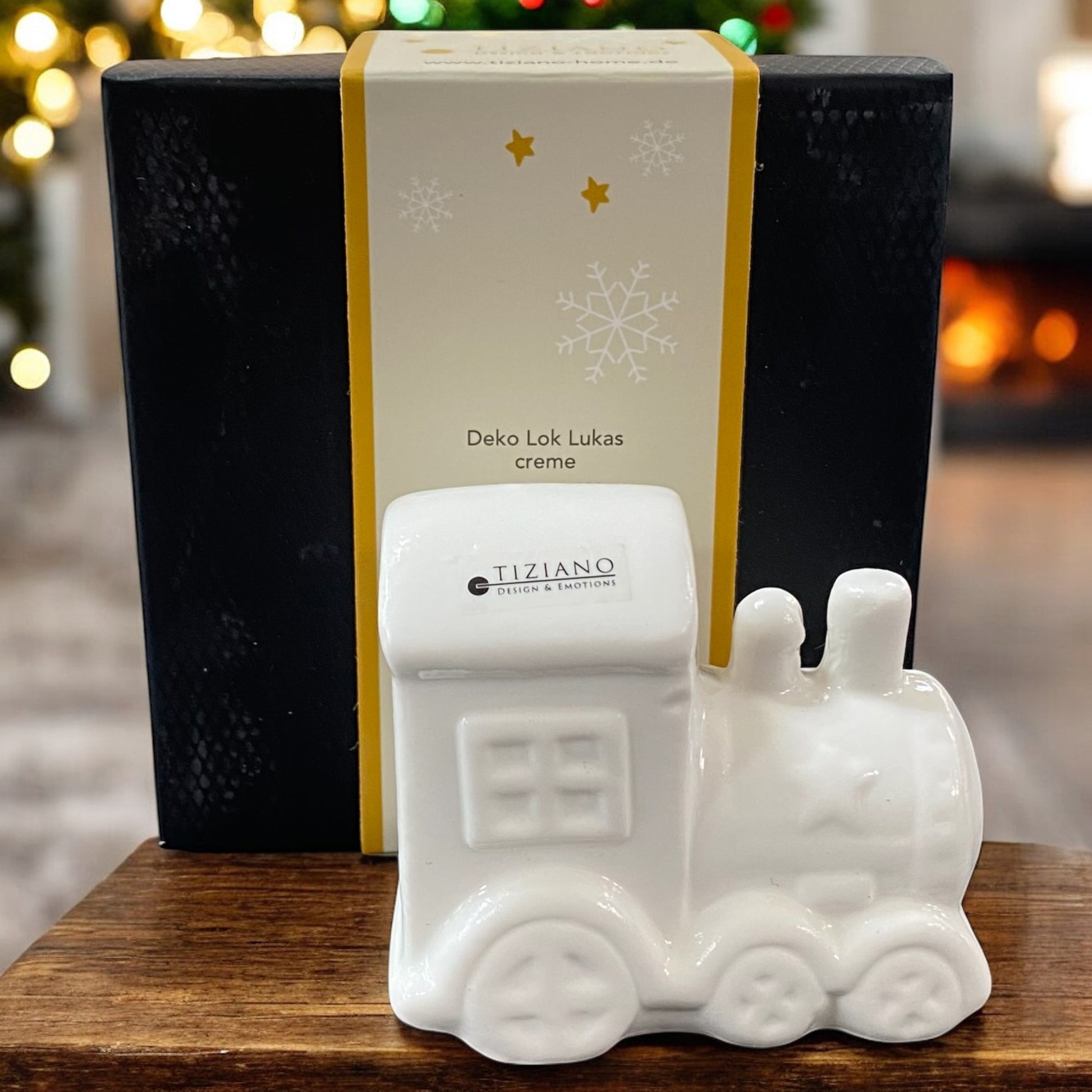 Tiziano Keramik-Lokomotive in Creme, weihnachtliche Dekoration mit Geschenkverpackung und Lichterhintergrund.