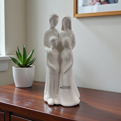 Weiße Keramikfigur mit stilisierter vierköpfiger Familie steht auf einem Möbelstück neben einer Zimmerpflanze.