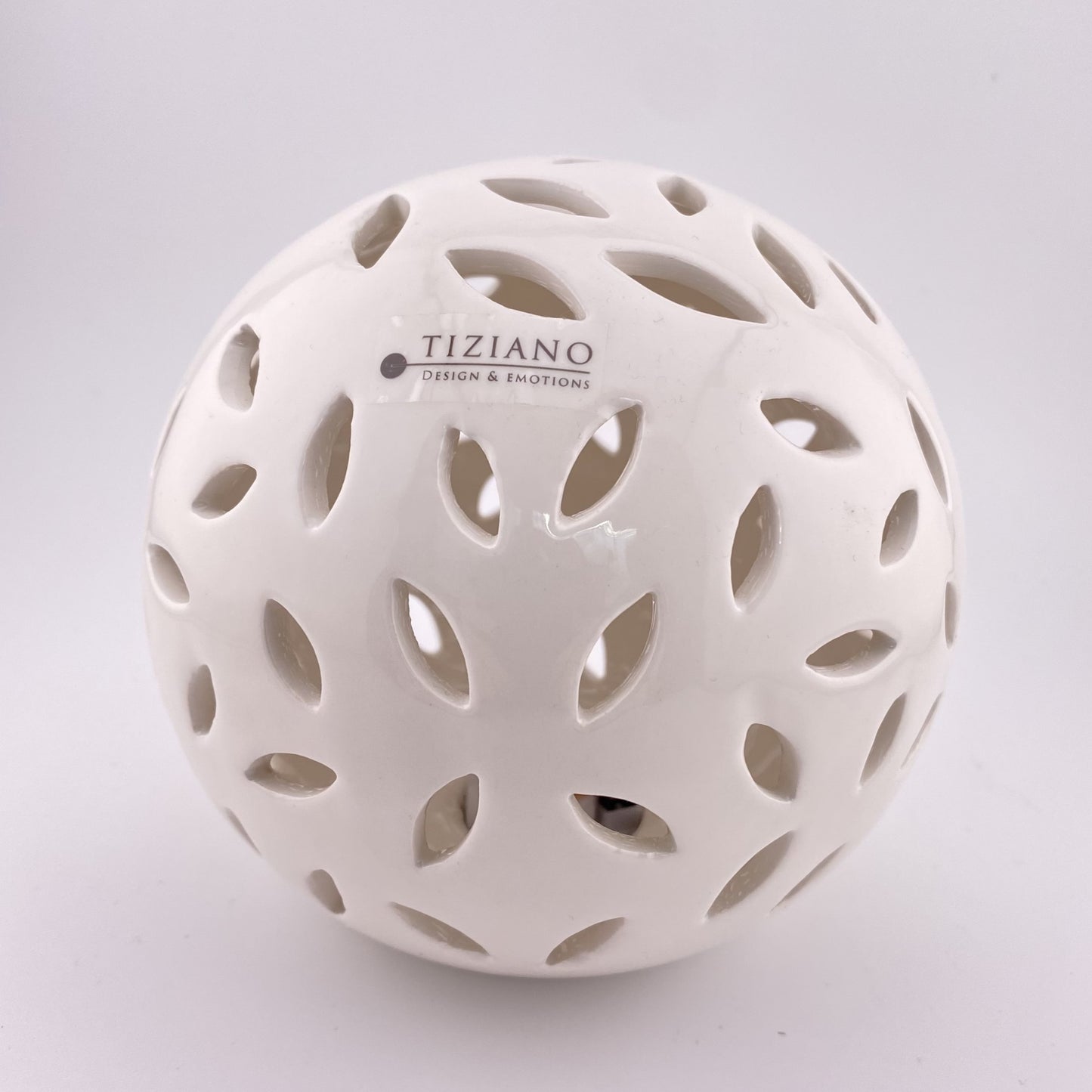 Eine große Dekokugel aus creme-weißer Keramik, die von innen mit einem LED Licht beleuchtet werden kann. Sie hat ovalförmige Aussparungen. Die Kugel 12cm groß und vor weißem Hintergrund platziert.