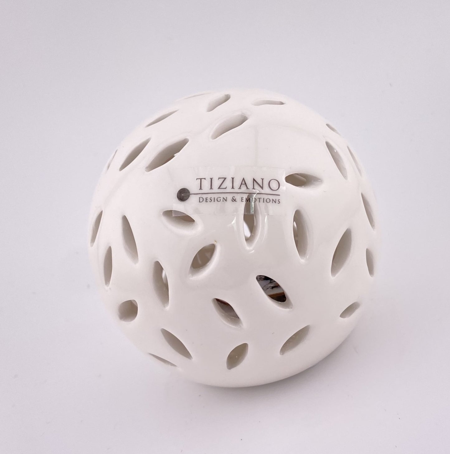 Eine kleine Dekokugel aus creme-weißer Keramik, die von innen mit einem LED Licht beleuchtet werden kann. Sie hat ovalförmige Aussparungen. Die Kugel 8cm groß und vor weißem Hintergrund platziert.