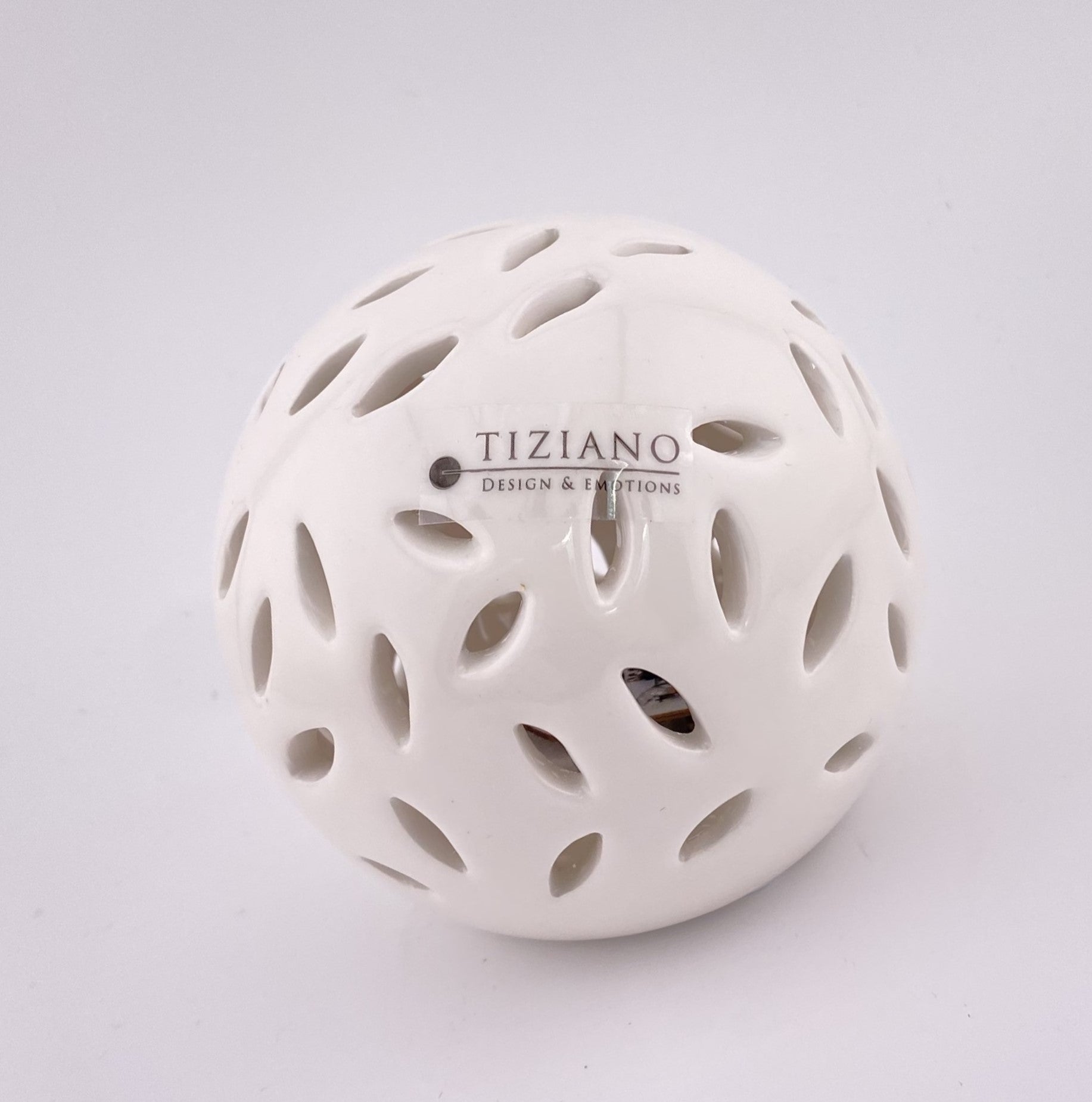 Eine kleine Dekokugel aus creme-weißer Keramik, die von innen mit einem LED Licht beleuchtet werden kann. Sie hat ovalförmige Aussparungen. Die Kugel 8cm groß und vor weißem Hintergrund platziert.