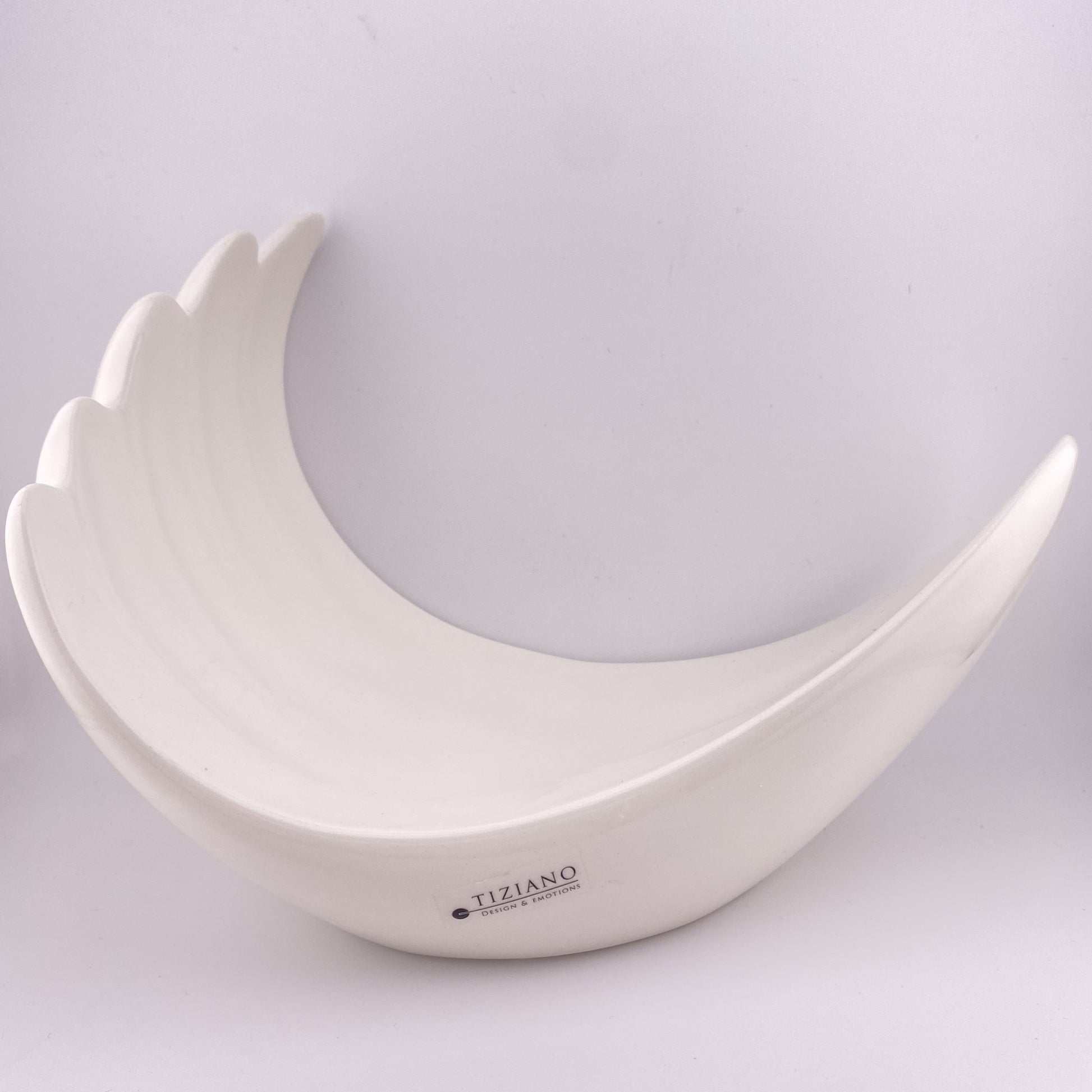 Eine dekorative, creme-weiße Keramik Schale vor weißem Hintergrund. Die Dekoschale ist 24cm groß und ist wie eine Welle geformt. 