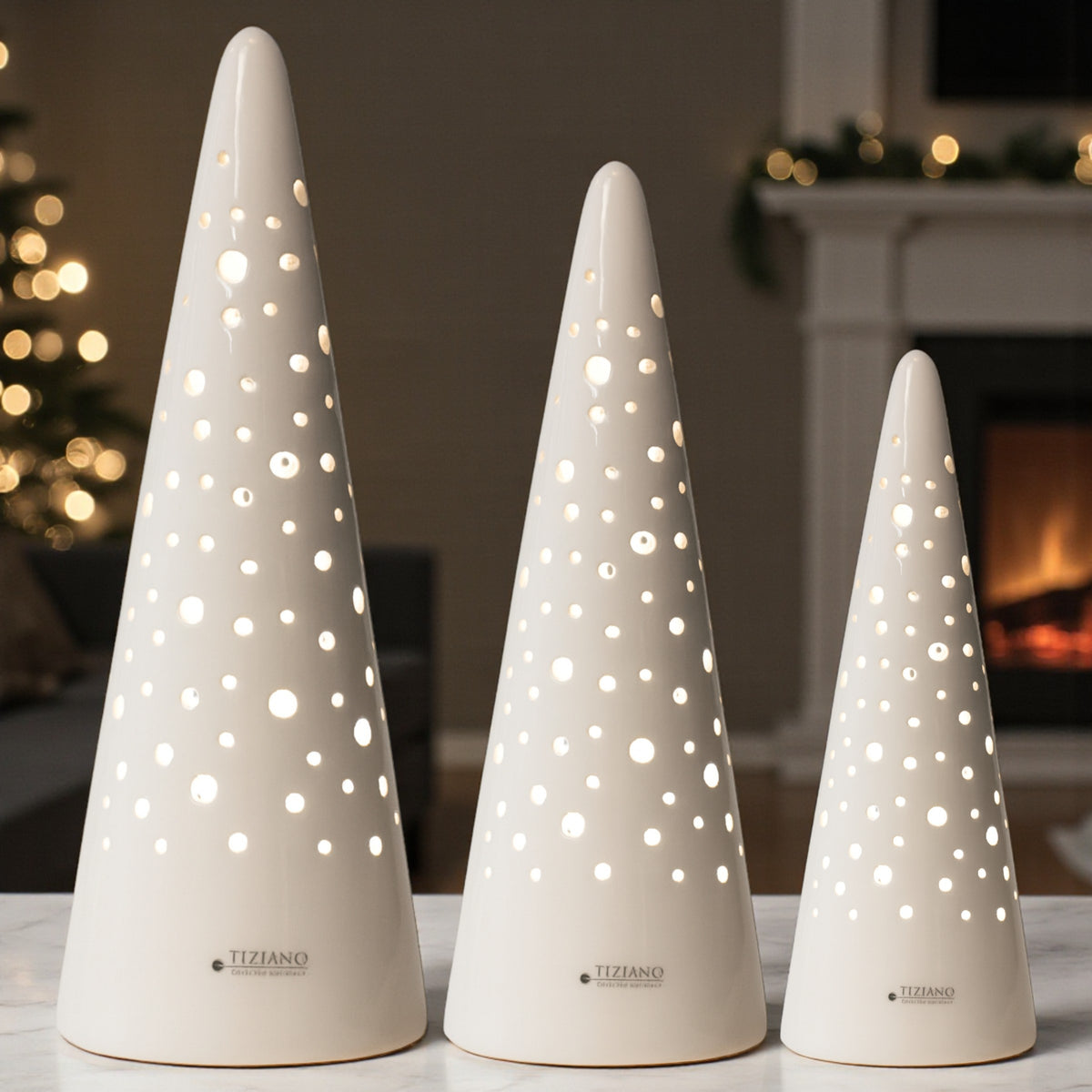 Drei unterschiedlich große, weiße Keramiklampen mit Lochmuster stehen auf einer hellen Oberfläche vor einem Kamin. Im Hintergrund sorgen Lichter und Dekoration für eine gemütliche Atmosphäre.