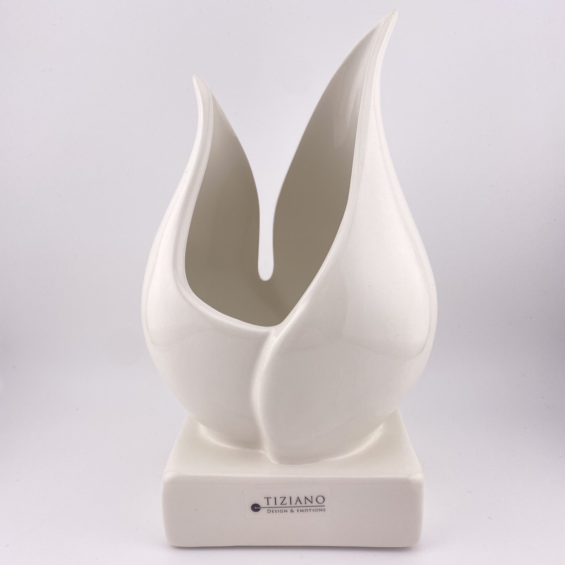 Eine Pflanzenschale aus creme-weißer Keramik vor weißem Hintergrund platziert. Die Vase besteht aus einem Sockel, auf dem zwei Blätter eine tulpenartige Vase und damit eine Öffnung formen. Die Keramikvase ist 20cm groß. 