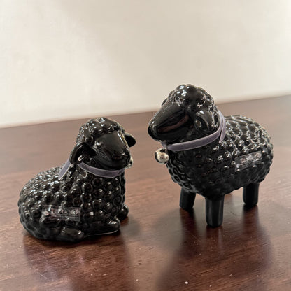 Schwarze Keramik-Schaffiguren liegend und stehend mit Halsband auf Tisch