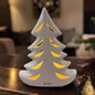 Cremeweißer Tiziano Keramik Tannenbaum mit warm beleuchteten geschwungenen Durchbrüchen auf einem dunklen Holztisch.