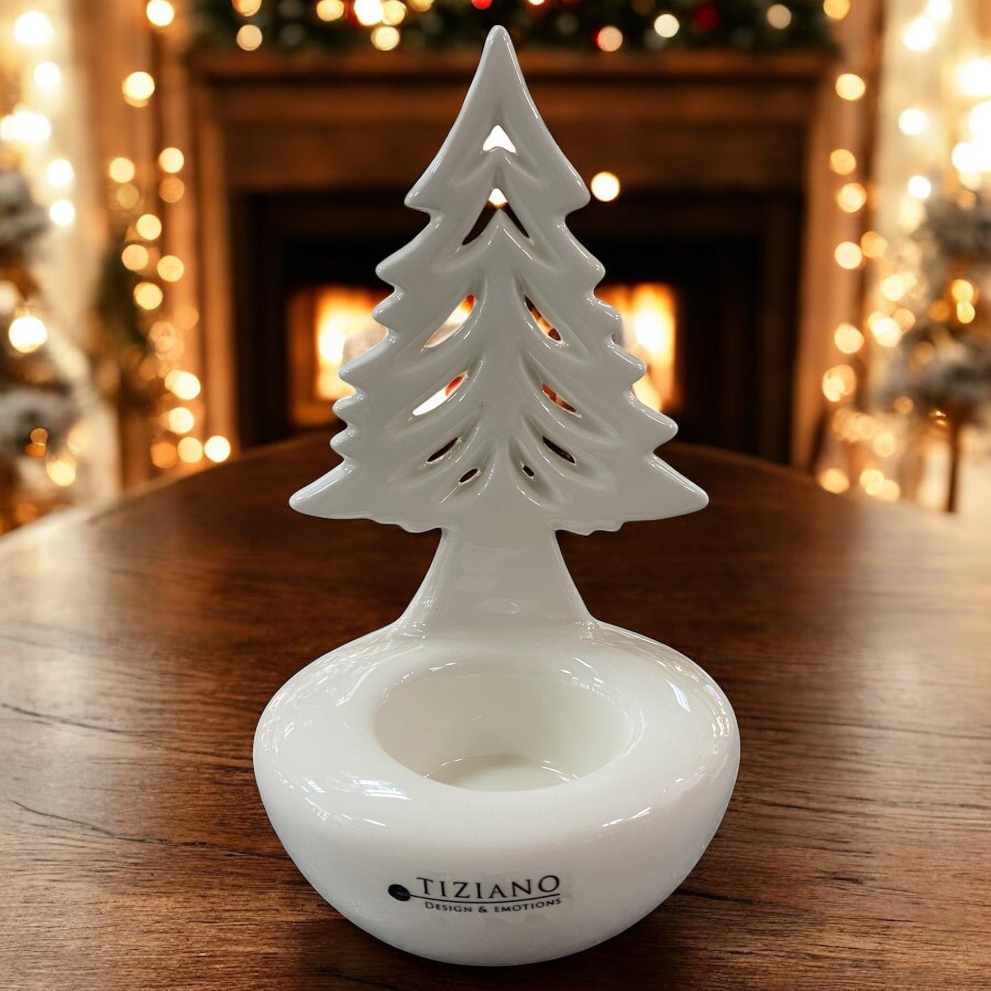 Weißer Keramik-Tannenbaum Joya von Tiziano als Teelichthalter, dekorativ auf Holztisch vor festlicher Beleuchtung.