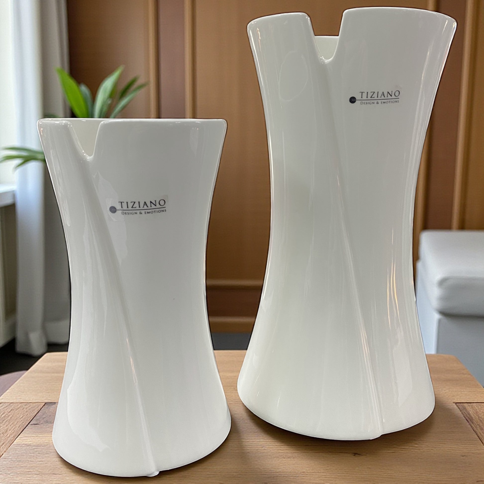 Zwei weiße Keramikvasen von Tiziano in unterschiedlichen Größen mit fließender Linienführung und asymmetrischem Rand, nebeneinander auf Holztisch