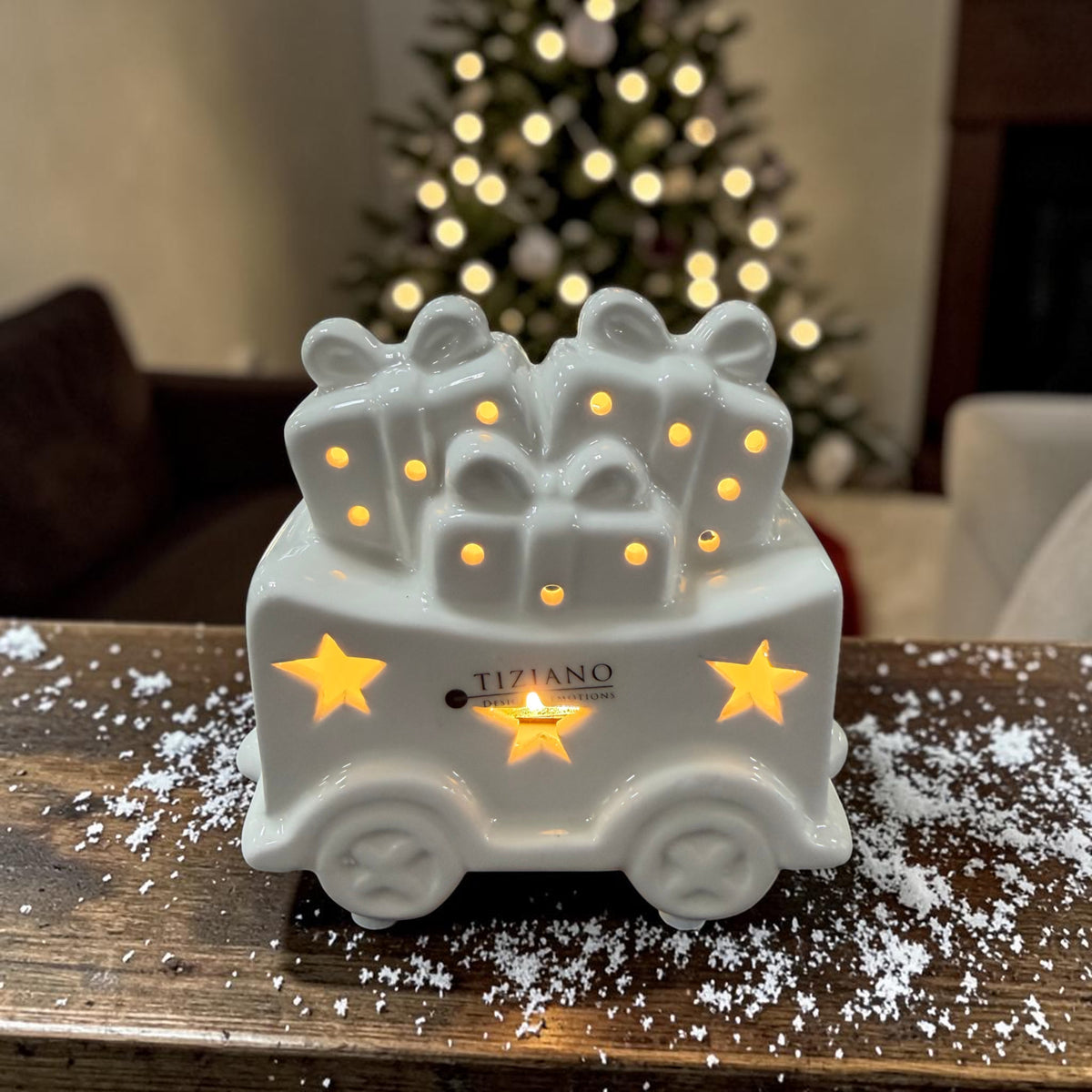 Cremeweißer Tiziano Keramik Weihnachtszug-Waggon mit Geschenken, Sternen und warmweißer Beleuchtung vor einem Weihnachtsbaum.