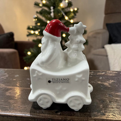 Cremeweißer Tiziano Keramik Weihnachtszug-Waggon mit Weihnachtsmann, roter Mütze und Tannenbaum vor einem beleuchteten Weihnachtsbaum.