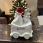 Cremeweißer Tiziano Keramik Weihnachtszug-Waggon mit Weihnachtsmann, roter Mütze und Tannenbaum vor einem beleuchteten Weihnachtsbaum.