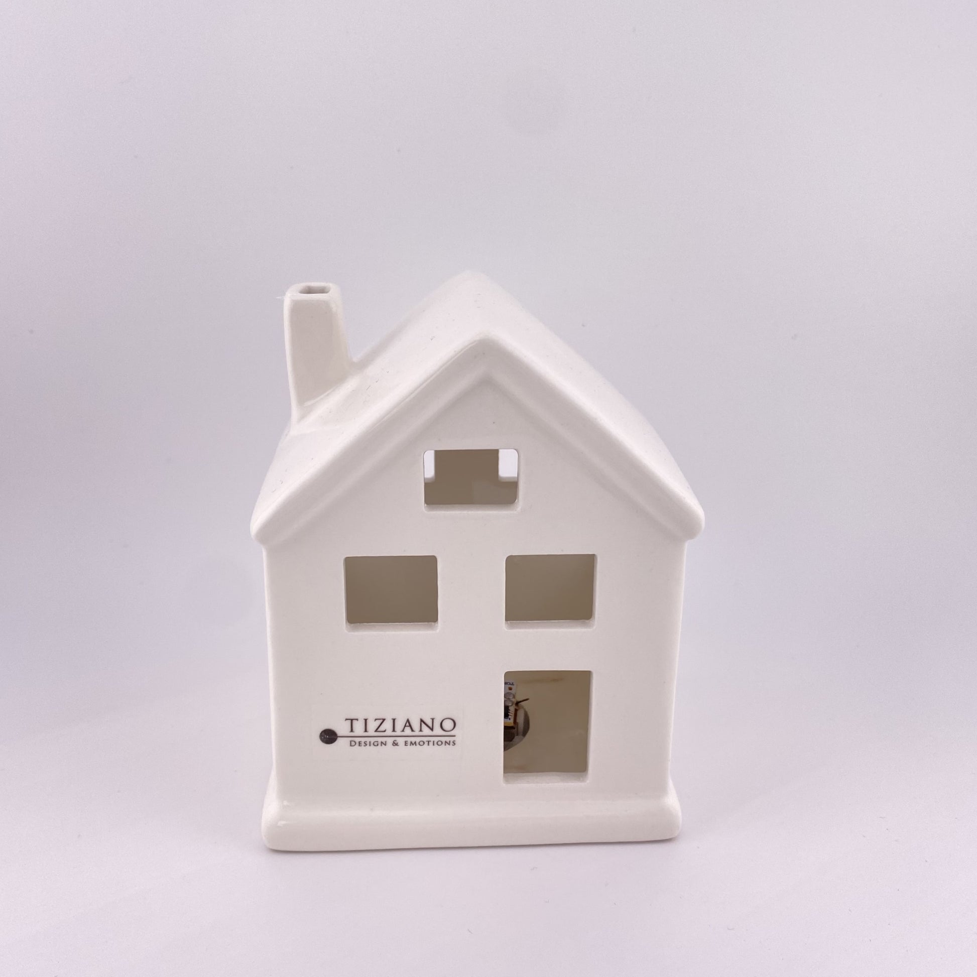 Ein kleines Keramik Deko Haus mit großen Fenstern, Türen und Schornstein aus creme-weißer Keramik gefertigt. Vor weißem Hintergrund platziert und 10cm groß.