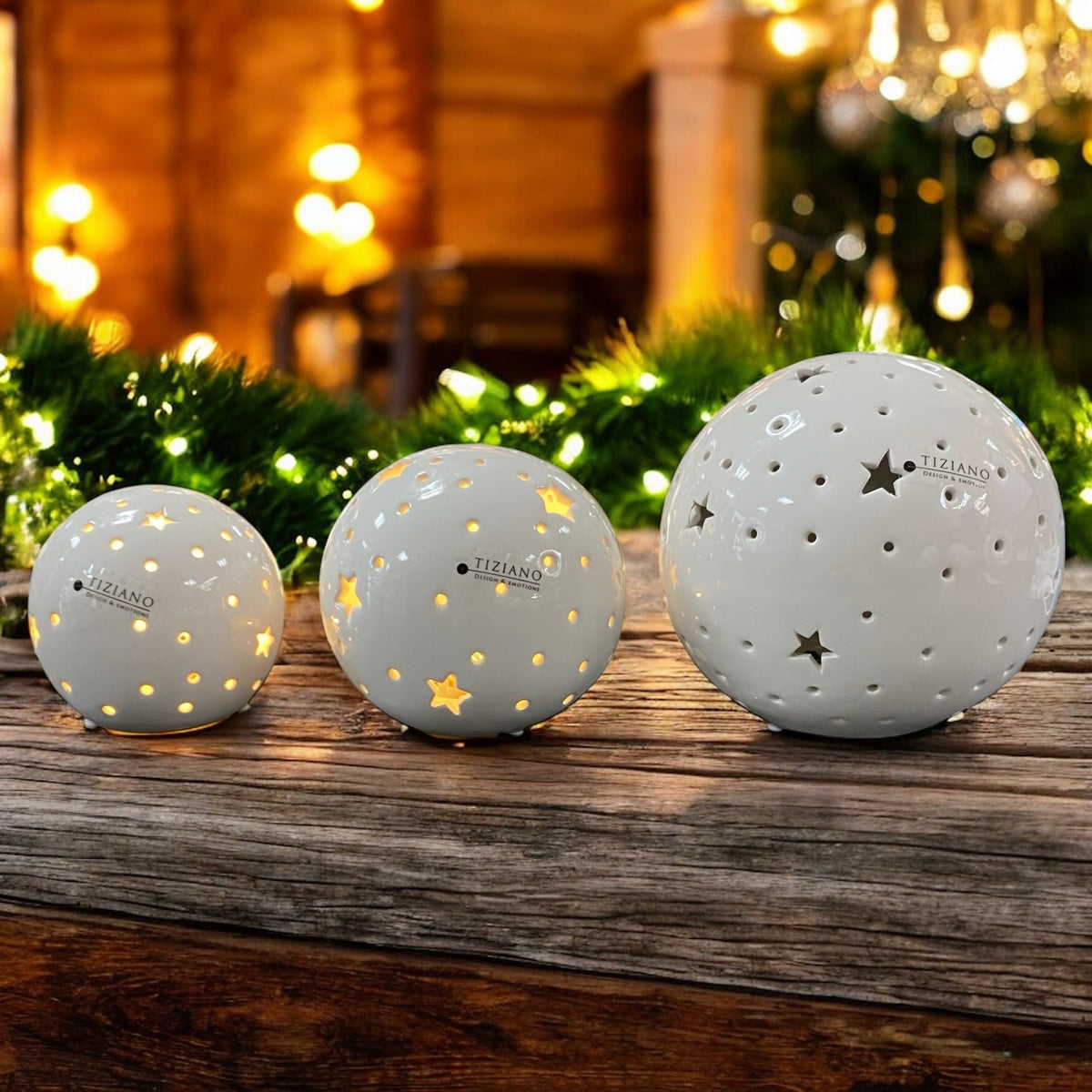 Tiziano LED-Kugeln Padova in drei Größen aus cremeweißer Keramik mit Sternenausschnitten, leuchtend im Winterambiente.