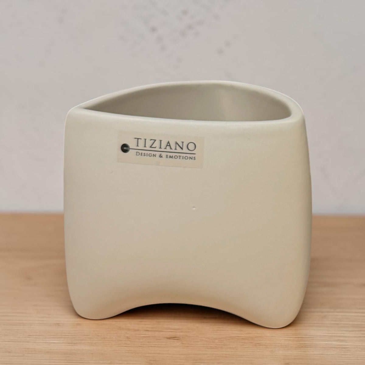 Kleines Tiziano Pflanzgefäß in Avena Beige mit abgerundeter Form auf einer hellen Holzfläche.