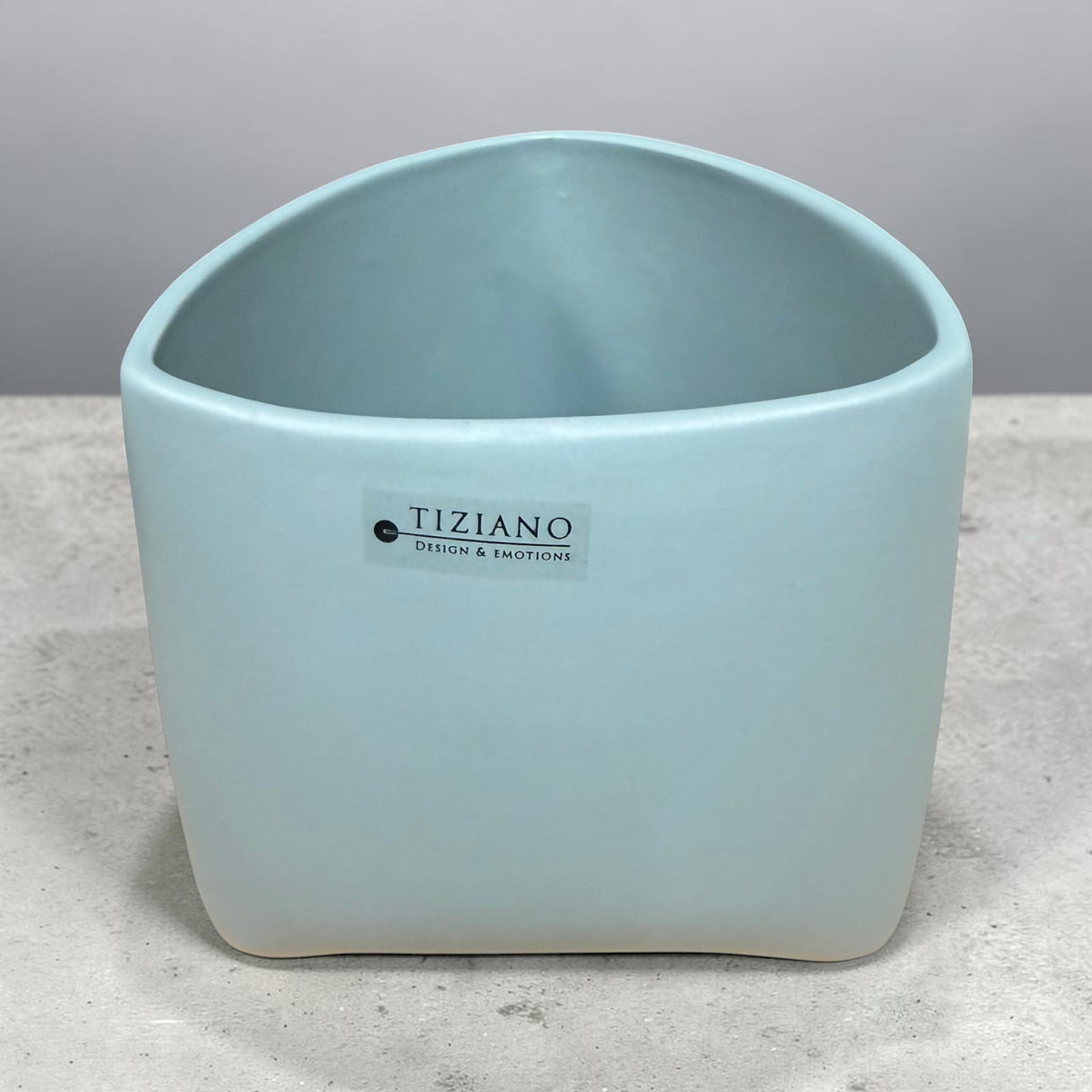 Großes Tiziano Pflanzgefäß in Laguna Blau mit abgerundeter rechteckiger Form und leicht geschwungener Öffnung auf grauem Untergrund.