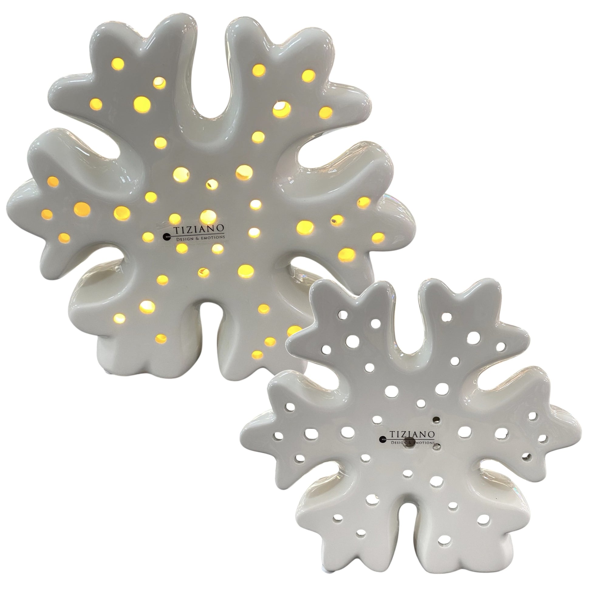 Zwei weiße Schneeflocken aus Keramik mit kleinen runden Öffnungen und integrierter LED-Beleuchtung. Die dekorativen Schneeflocken stehen nebeneinander und leuchten warmweiß. Auf der Vorderseite ist das Logo „Tiziano Design & Emotions“ zu sehen.