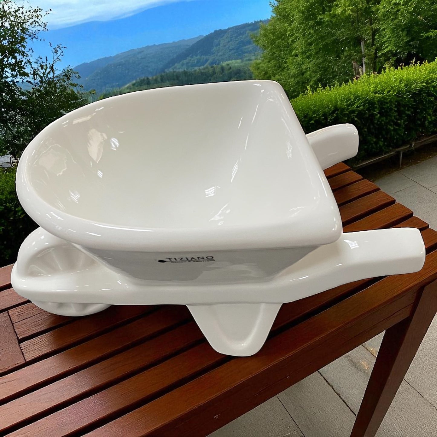 Eine Tiziano Pflanzschale in Form einer creme-weißen Keramik Schubkarre mit Rad und Griffen im Ambiente von oben