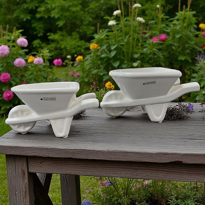 Zwei Tiziano Pflanzschalen in Form einer creme-weißen Keramik Schubkarre mit Rad und Griffen im Ambiente