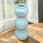 Große Tiziano Vase in Laguna Blau mit drei abgerundeten Formelementen auf einem Holztisch vor hellem Hintergrund.