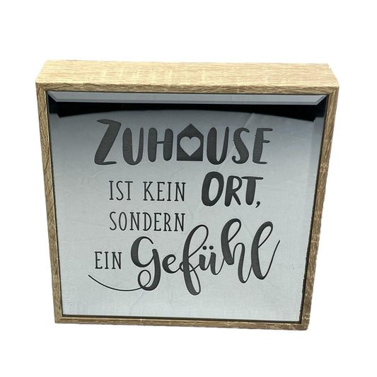 Spiegelbild mit der Aufschrift Zuhause ist kein Ort sondern ein Gefühl. Zum hinstellen oder aufhängen. Vor weißem Hintergrund 